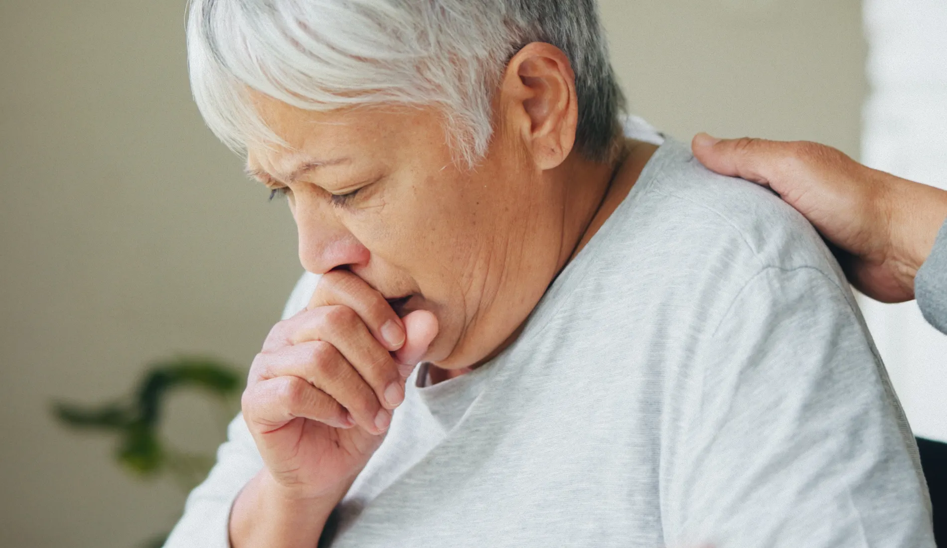 Personne la main sur la bouche en train de tousser, illustrant la toux chronique et la gêne respiratoire caractéristiques de la broncho-pneumopathie chronique obstructive (BPCO)