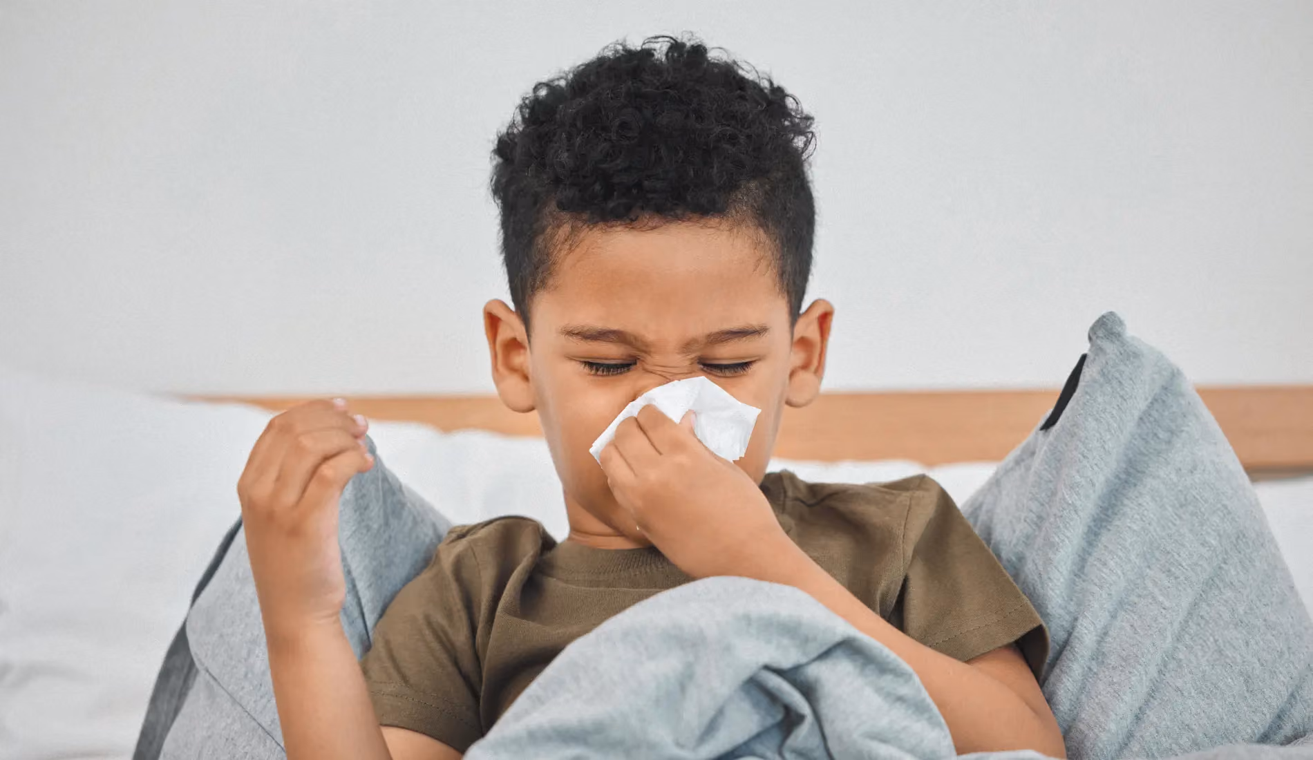 Un enfant alité et qui se mouche, signe évocateur du bronchospasme post-viral chez l'enfant.