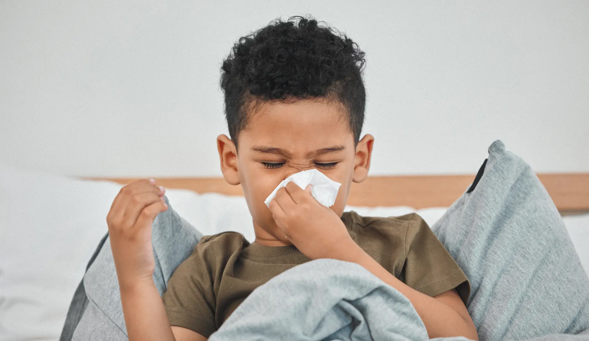 Un enfant alité et qui se mouche, signe évocateur du bronchospasme post-viral chez l'enfant.