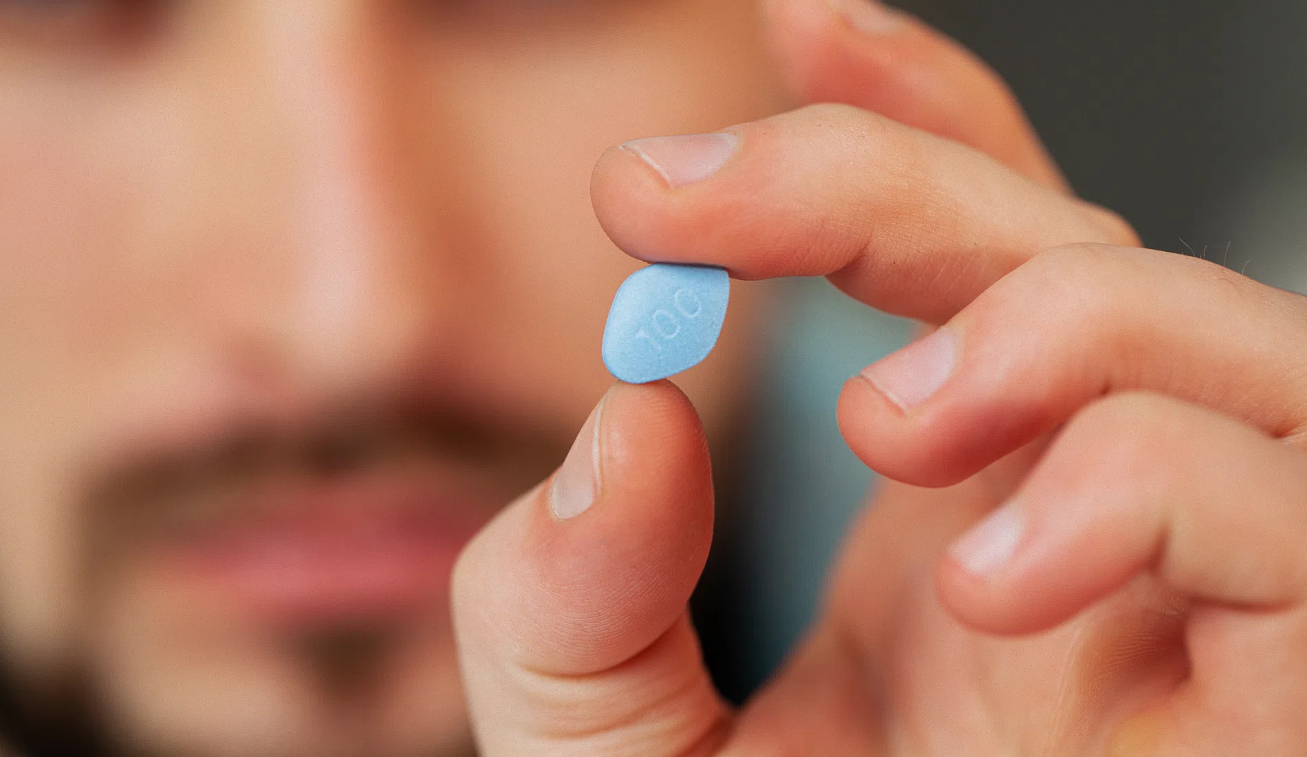 Zoom sur un comprimé de viagra tenu par un homme, signe de l'intérêt d'obtenir du sildénafil en cas de dysfonction érectile
