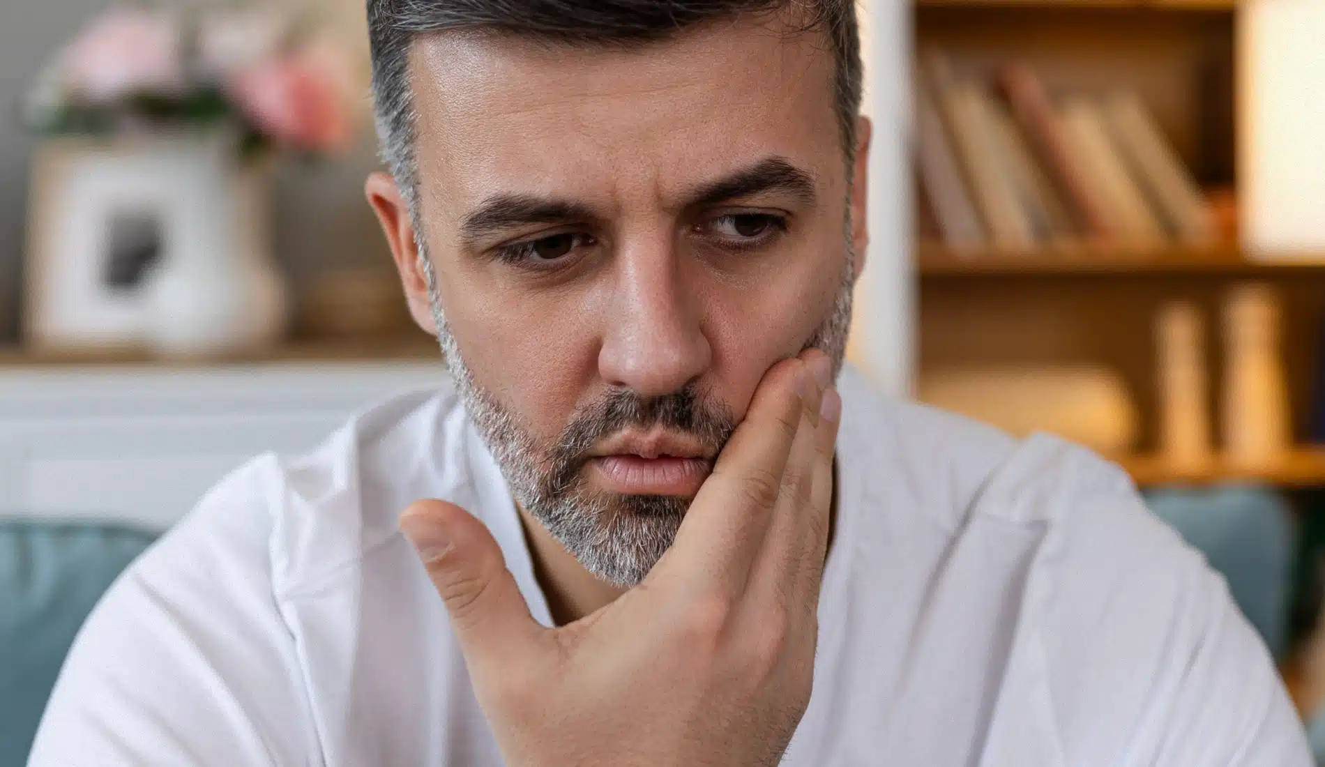 Une personne à l'air anxieux qui se touche sa joue, signe d'un abcès dentaire.