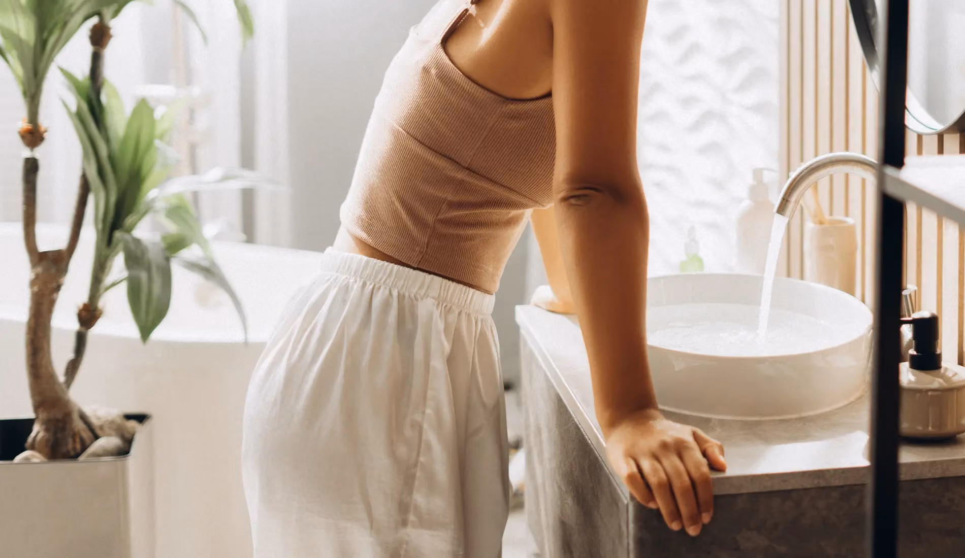 Une femme penchée sur son lavabo, en train de penser à une solution pour ses pertes jaunes.