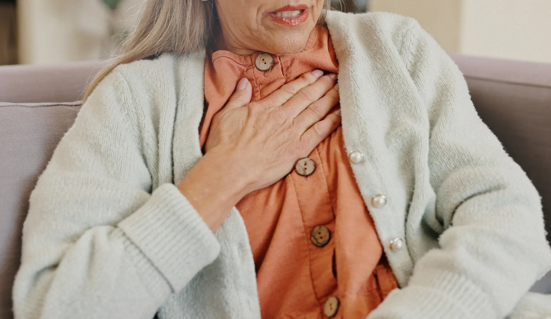 Femme assise, main posée sur son coeur, car ce dernier s'emballe.
