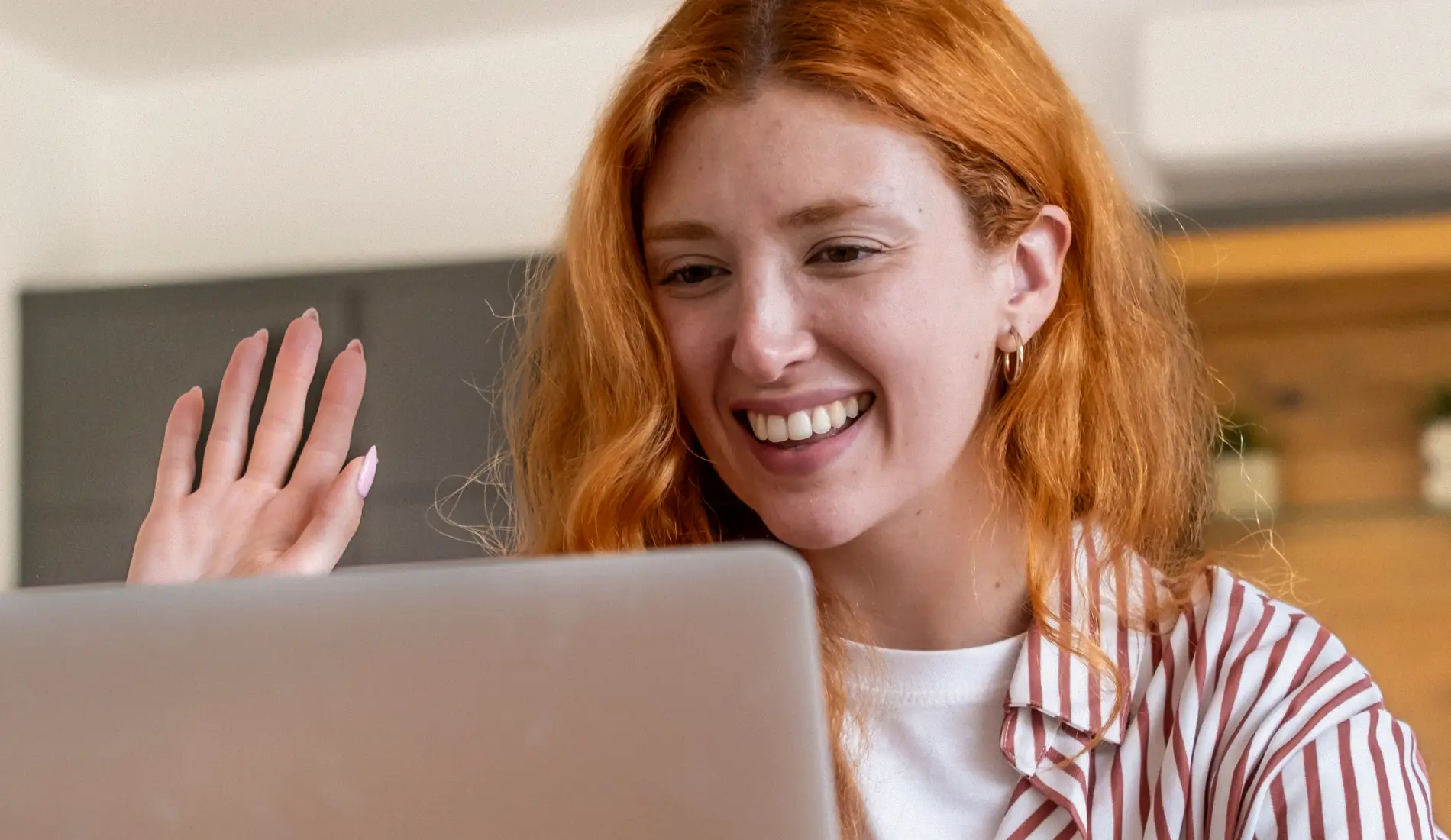 Une jeune femme souriante, assise devant son ordinateur, en train de faire une téléconsultation pour IVG médicamenteuse