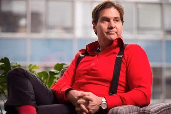 Homem branco de cabelo castanho com camisa vermelha sentado em uma poltrona