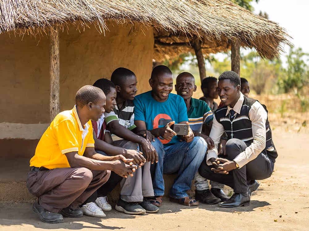 Villagers gathered around an audio device listening to the Bible