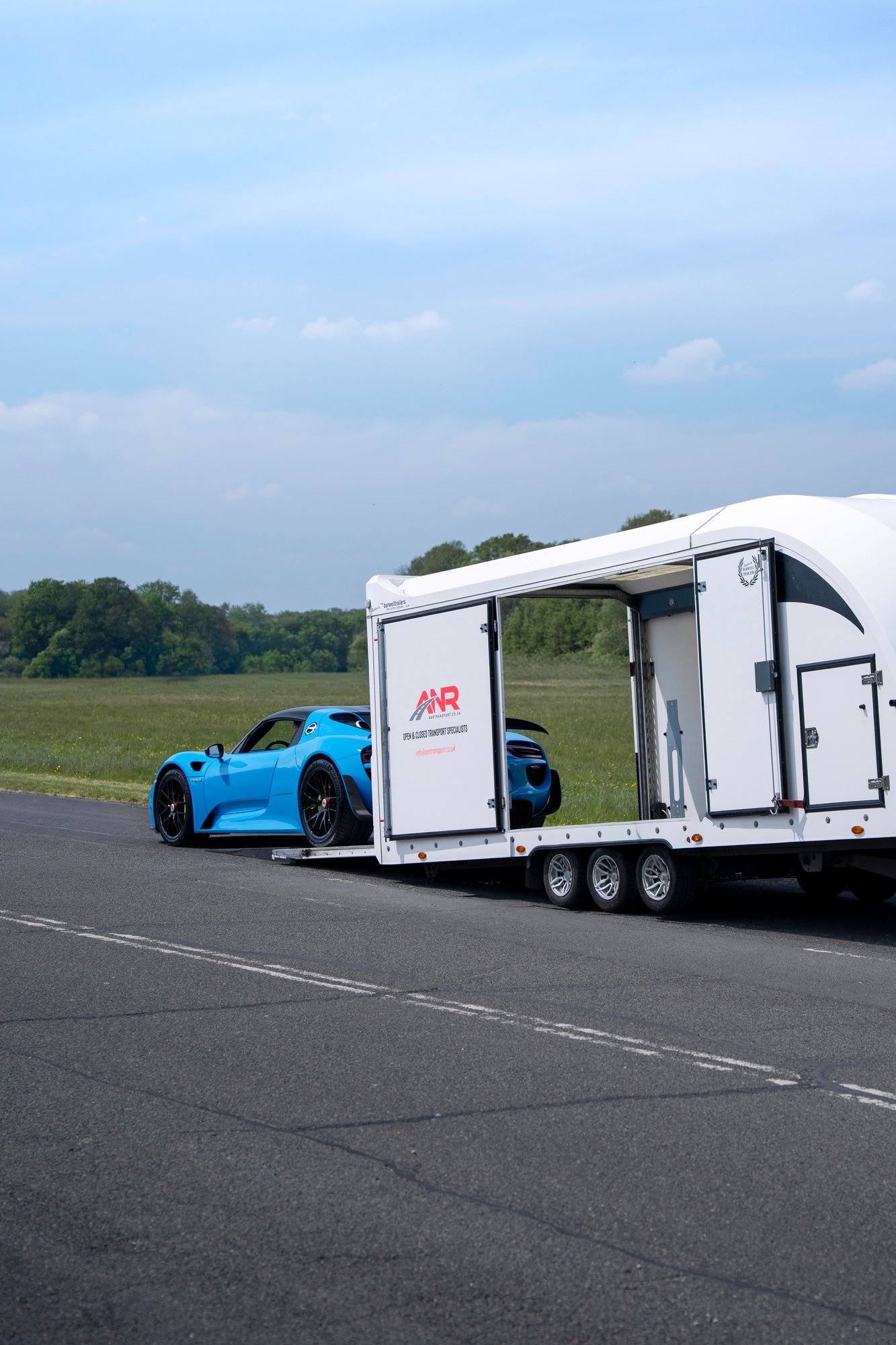 Porsche 918 Spyder being loaded into an enclosed transport trailer