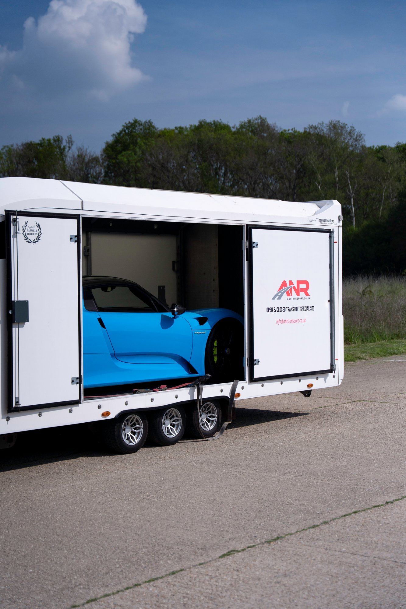 Blue Porsche 918 Spyder secured inside an enclosed transport trailer