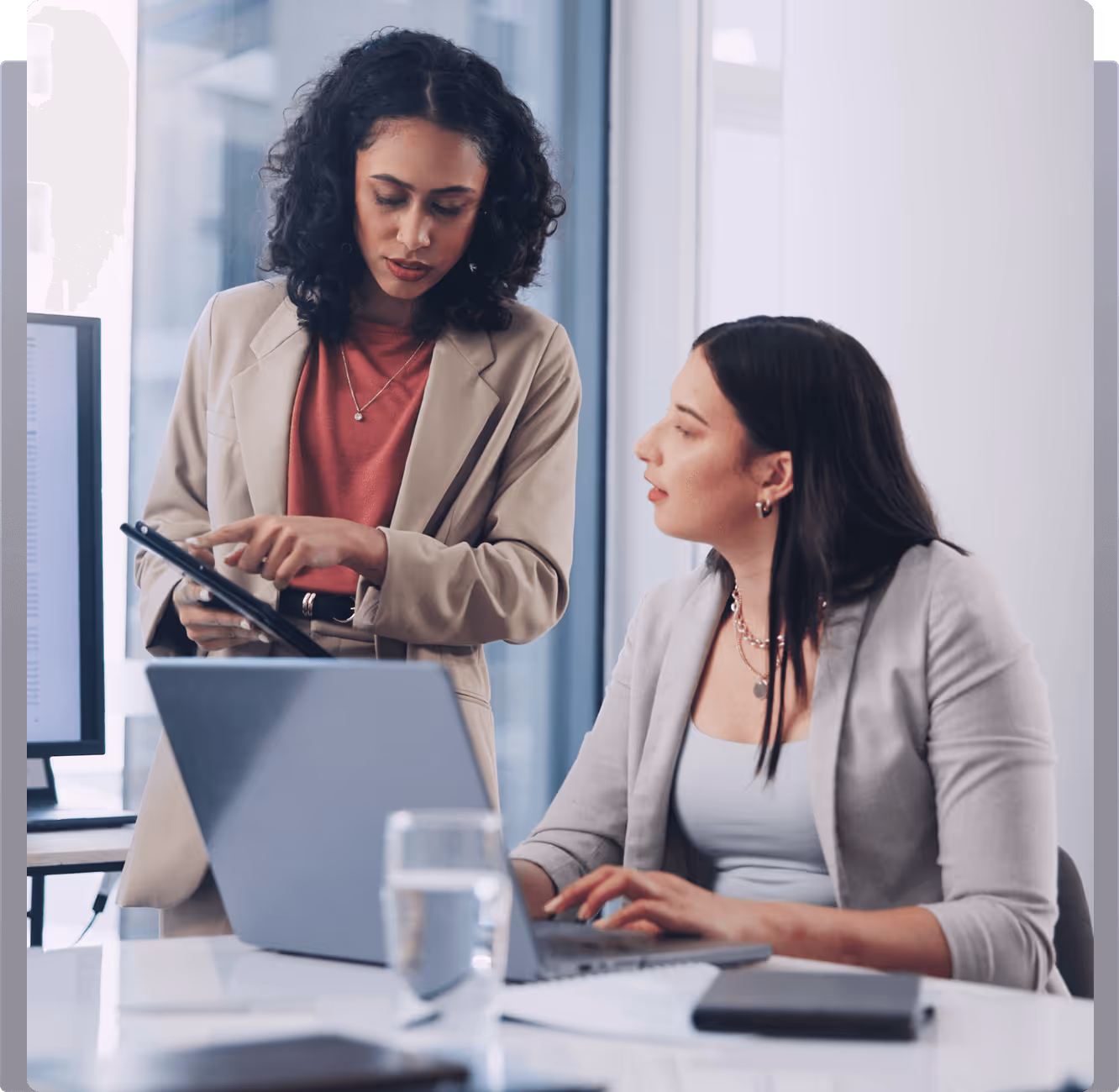 Two women sitting at a table looking at a laptop
