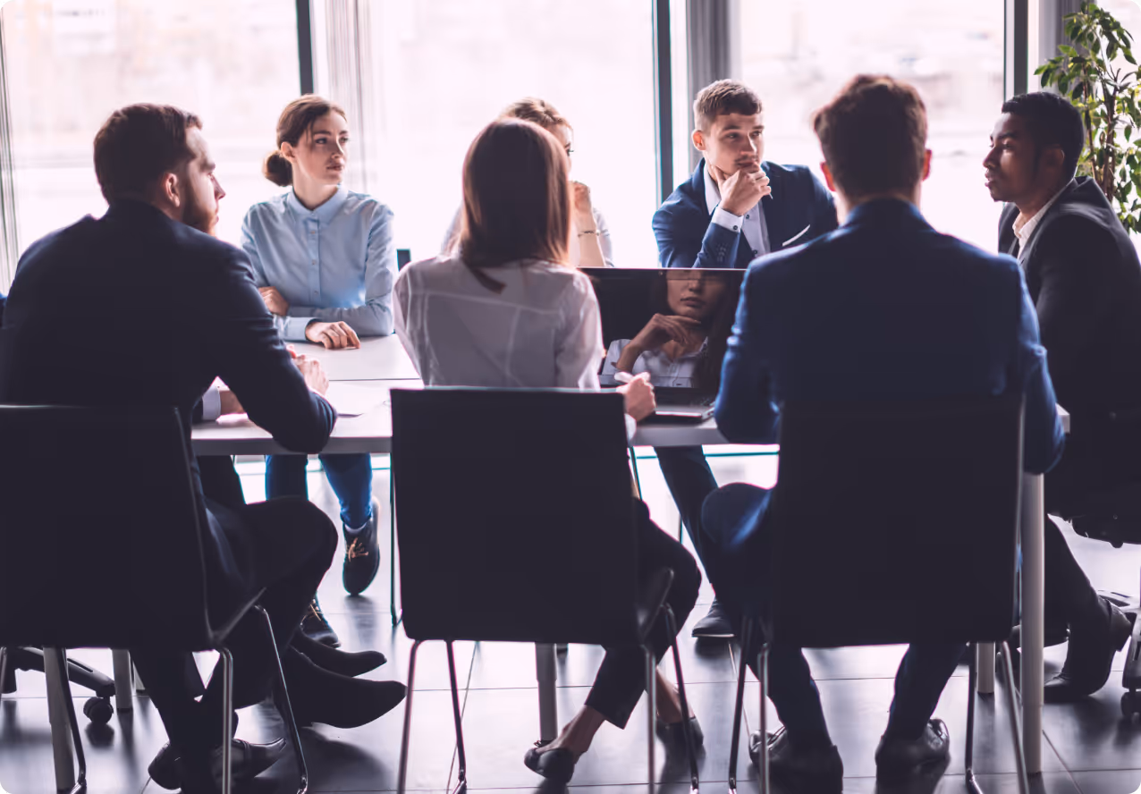 A group of people in a business meeting sitting around a table.