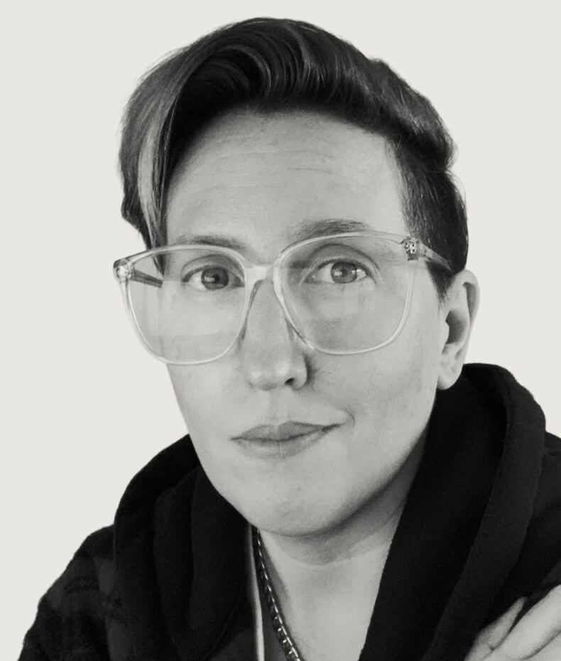 Portrait of Kellie, a white woman with short dark hair and clear glasses, wearing a dark hoodie.