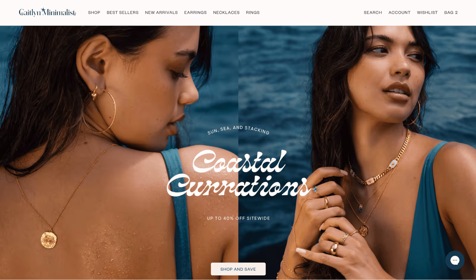 Caitlyn Minimalist homepage showing women wearing layered gold jewelry, including hoop earrings, necklaces, and rings, posing by the ocean with the text "Coastal Curations – Up to 40% Off Sitewide."