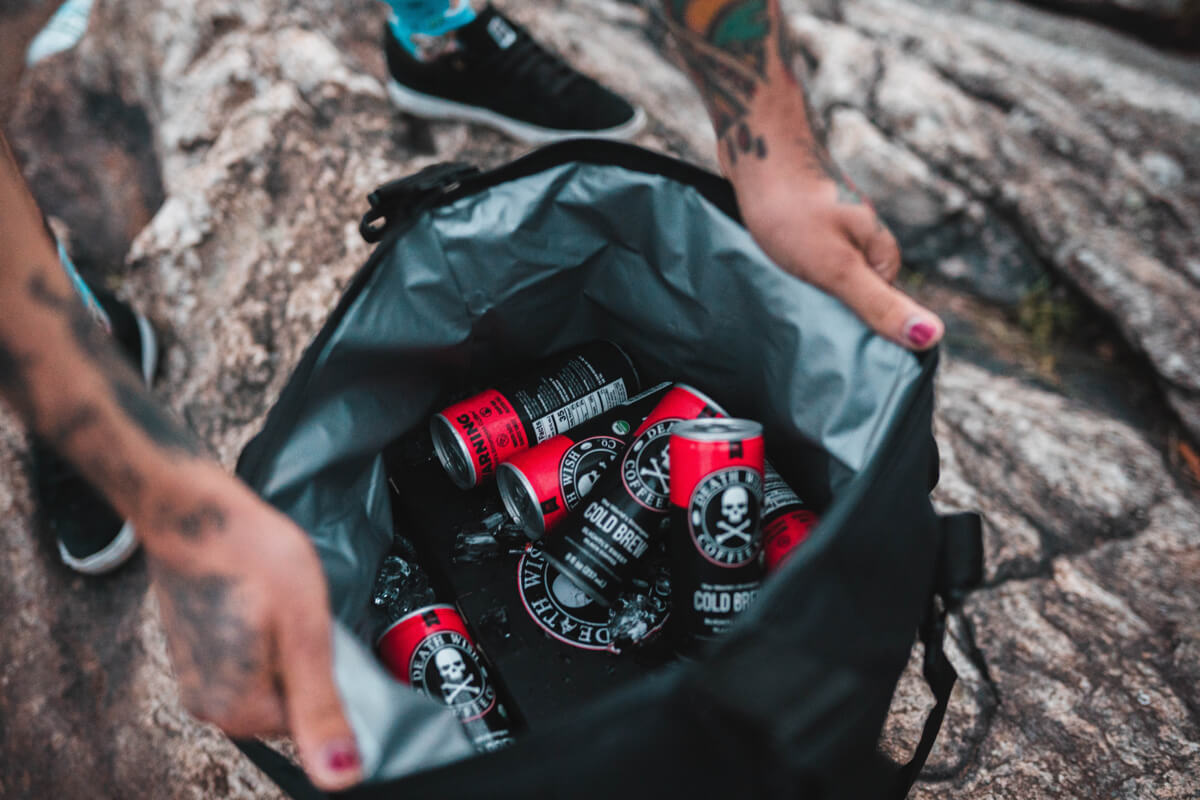 Cans of Death Wish Cold Brew Coffee in a backpack on a hike. Death Wish Coffee use Gorgias for Customer Support