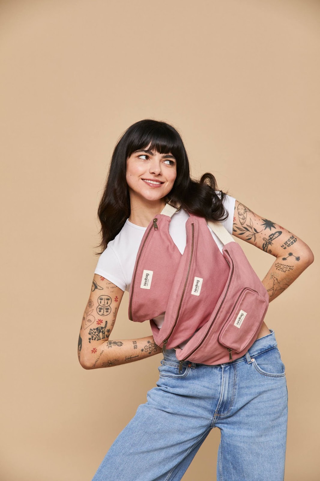 An image of a woman posing with three pink Hindbag banana, belt bags across her chest. 