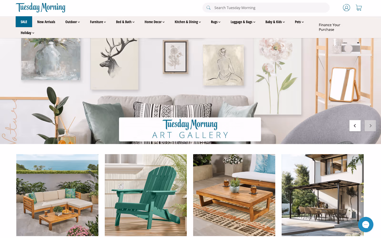 Tuesday Morning homepage showing navigation menu and featured product images including wall art, outdoor seating, and wooden furniture.