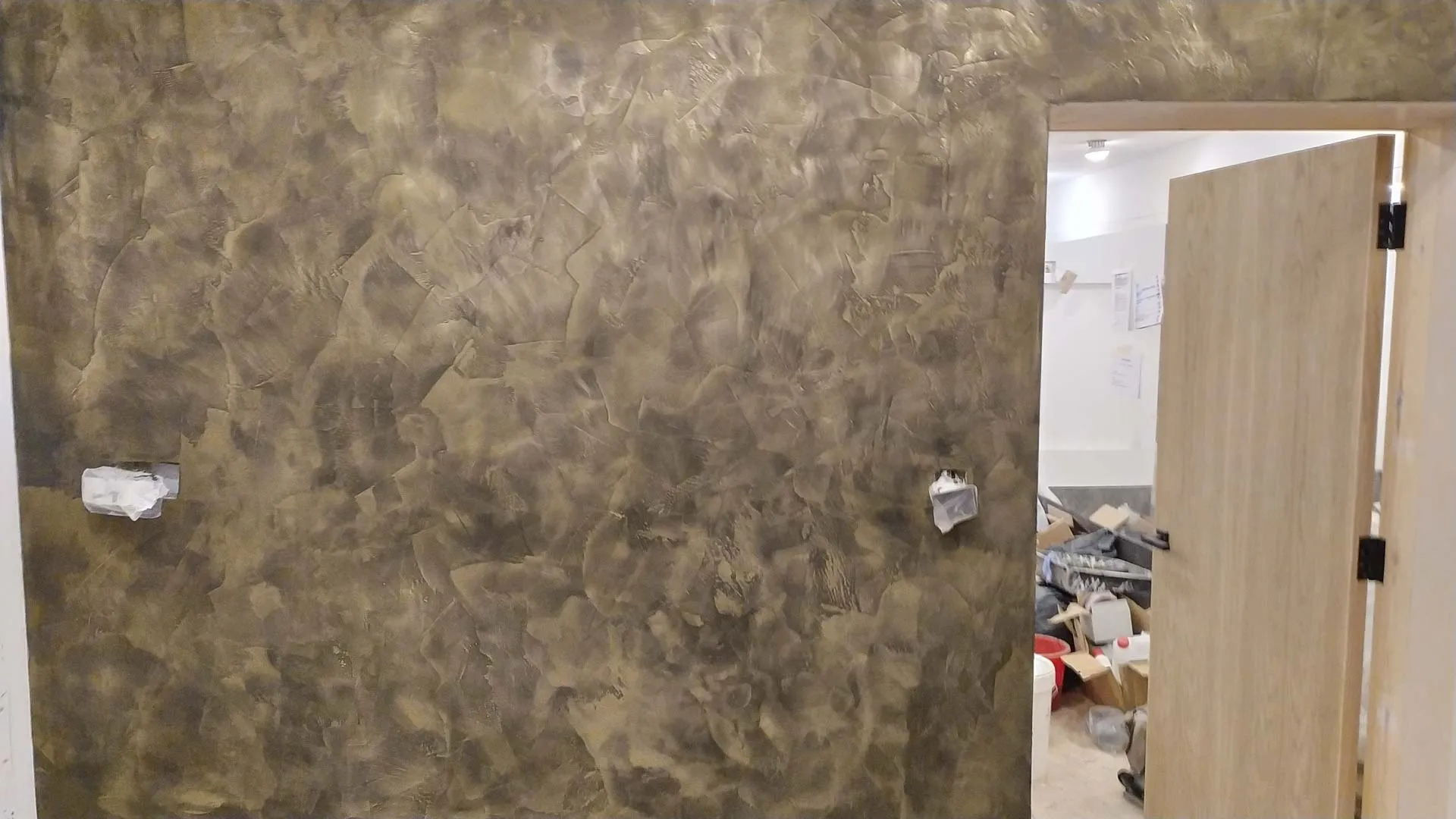Wall finished in metallic bronze microcement beside a doorway