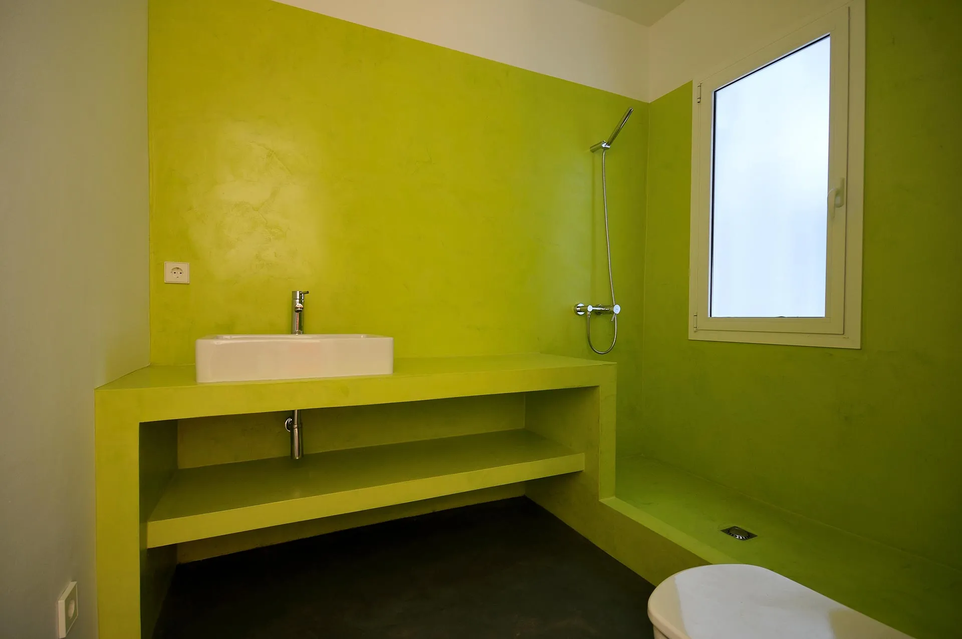 Lime green microcement bathroom with built-in vanity shelf and walk-in shower