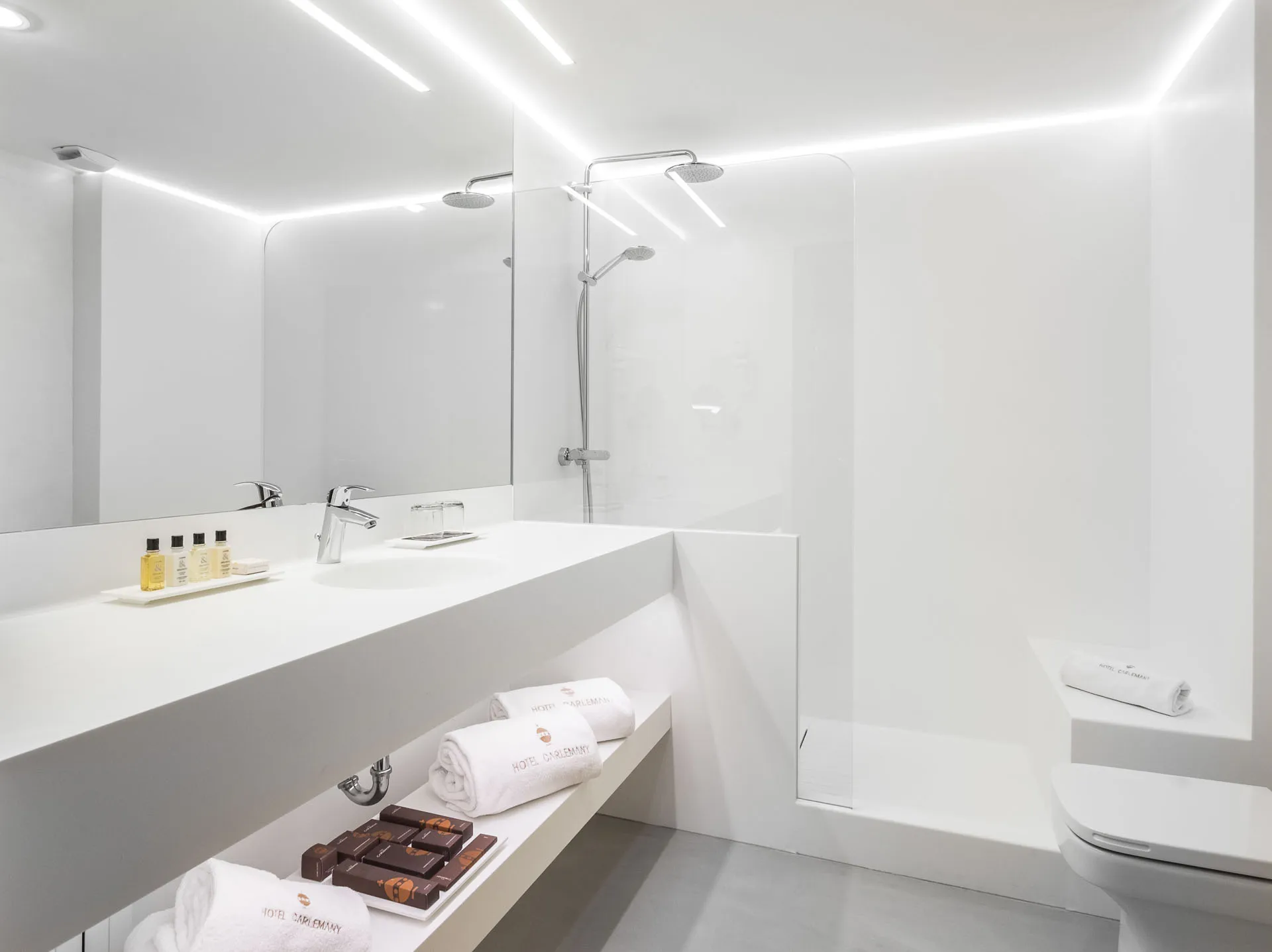 White microcement bathroom with long vanity, walk-in shower and LED ceiling strips