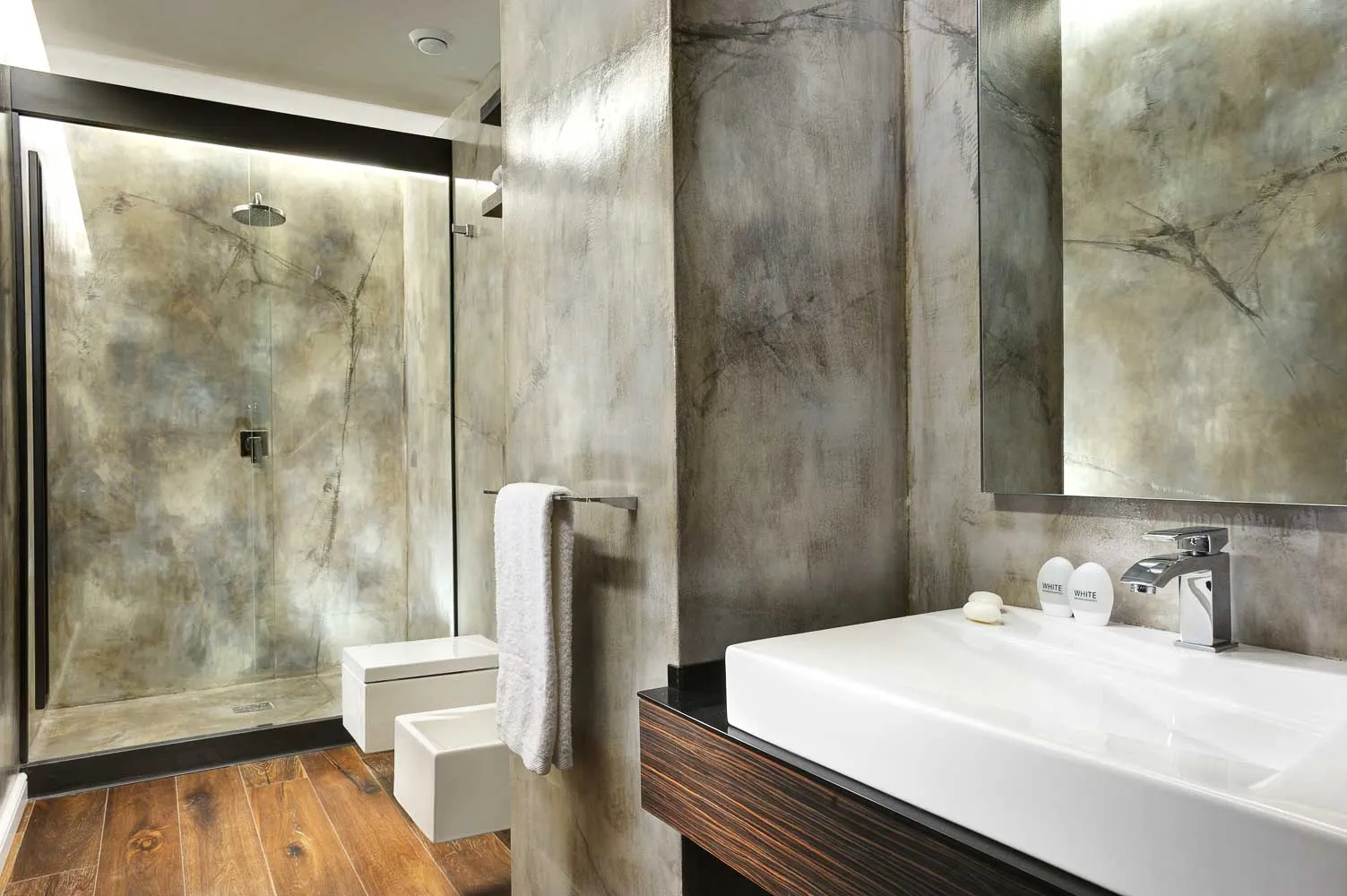 Bathroom with marbled grey microcement walls, walk-in shower and wide white basin