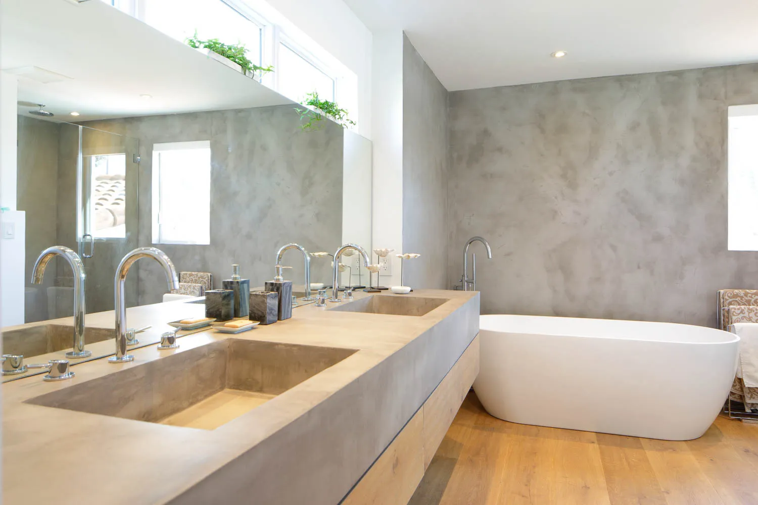 Bathroom with grey microcement walls and double-basin vanity beside a freestanding bath