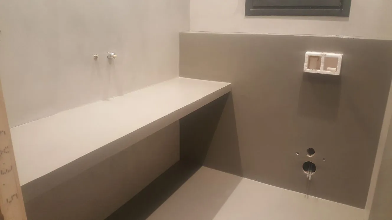 Grey microcement bathroom walls and floating vanity shelf during installation