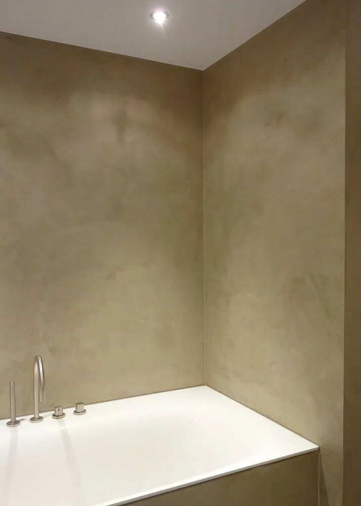 Beige microcement bathroom walls around a white built-in bath