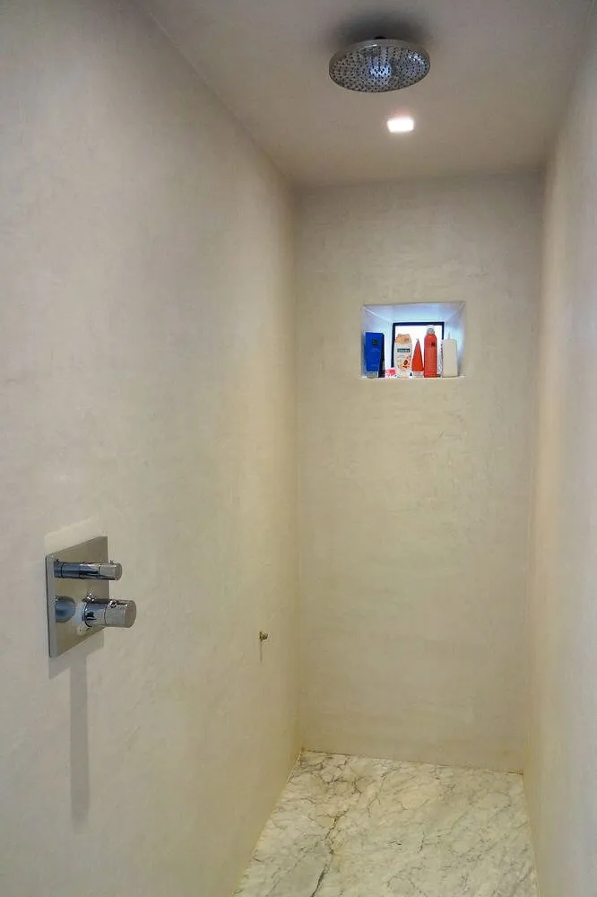 Cream microcement walk-in shower with recessed niche and rainfall head