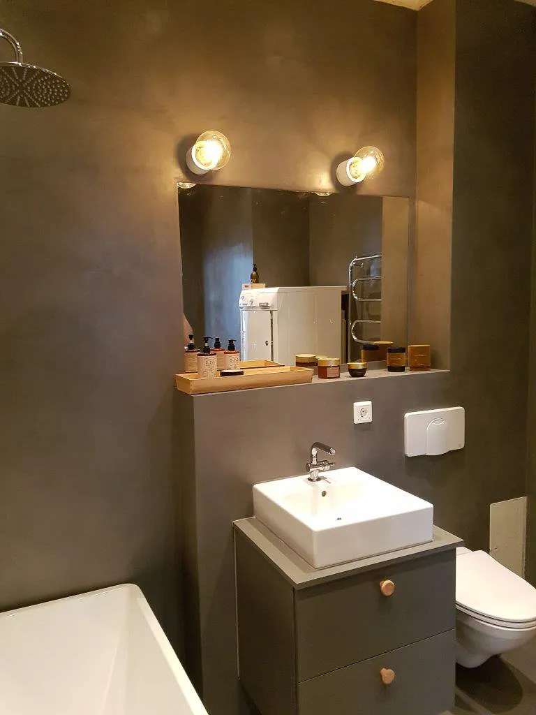 Taupe microcement bathroom walls with basin vanity, mirror and wall lights