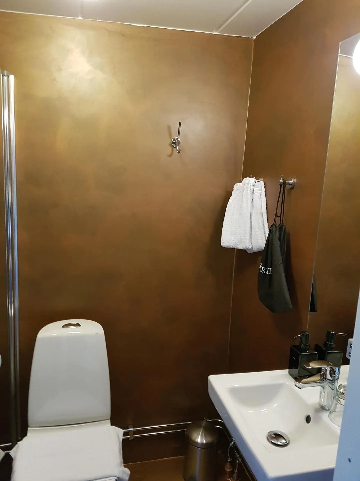 Small bathroom with bronze metallic microcement walls, toilet and basin
