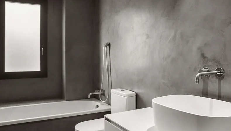 Grey microcement bathroom walls with bath, WC and white vessel basin