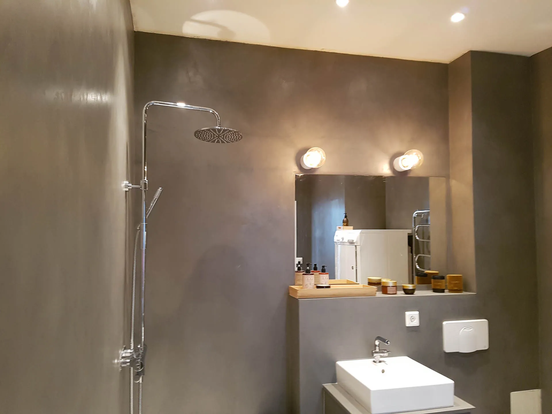 Taupe microcement bathroom walls with rainfall shower, mirror and white basin