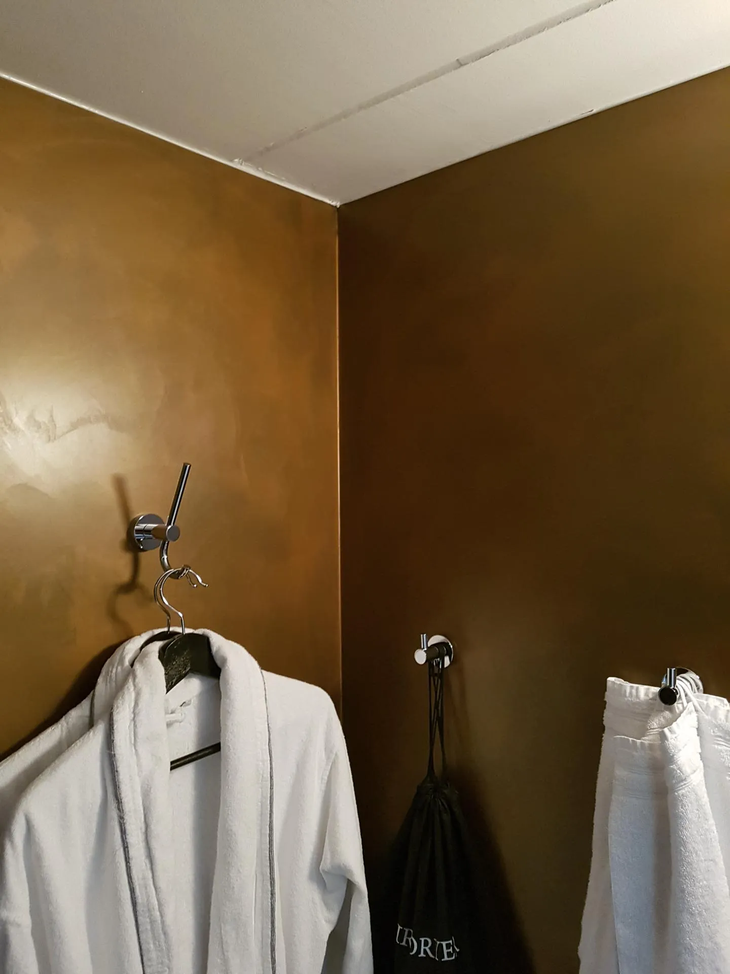 Bronze metallic microcement bathroom walls with robe hooks