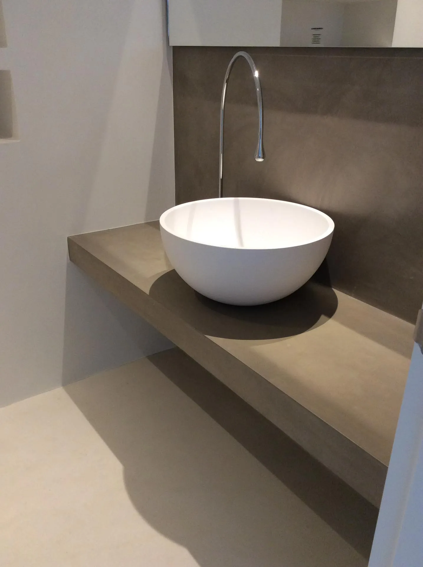 Floating microcement vanity shelf with a white bowl basin and tall spout tap