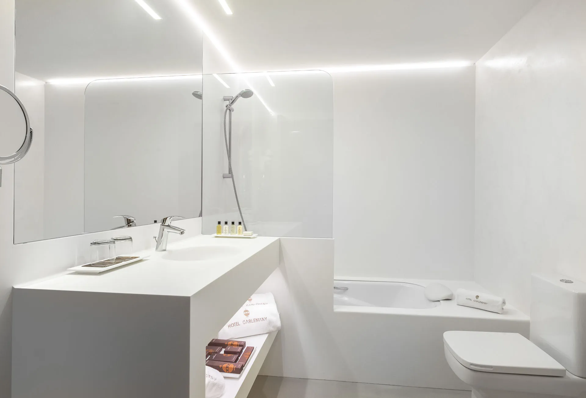 White microcement bathroom with integrated vanity, bath and shower screen
