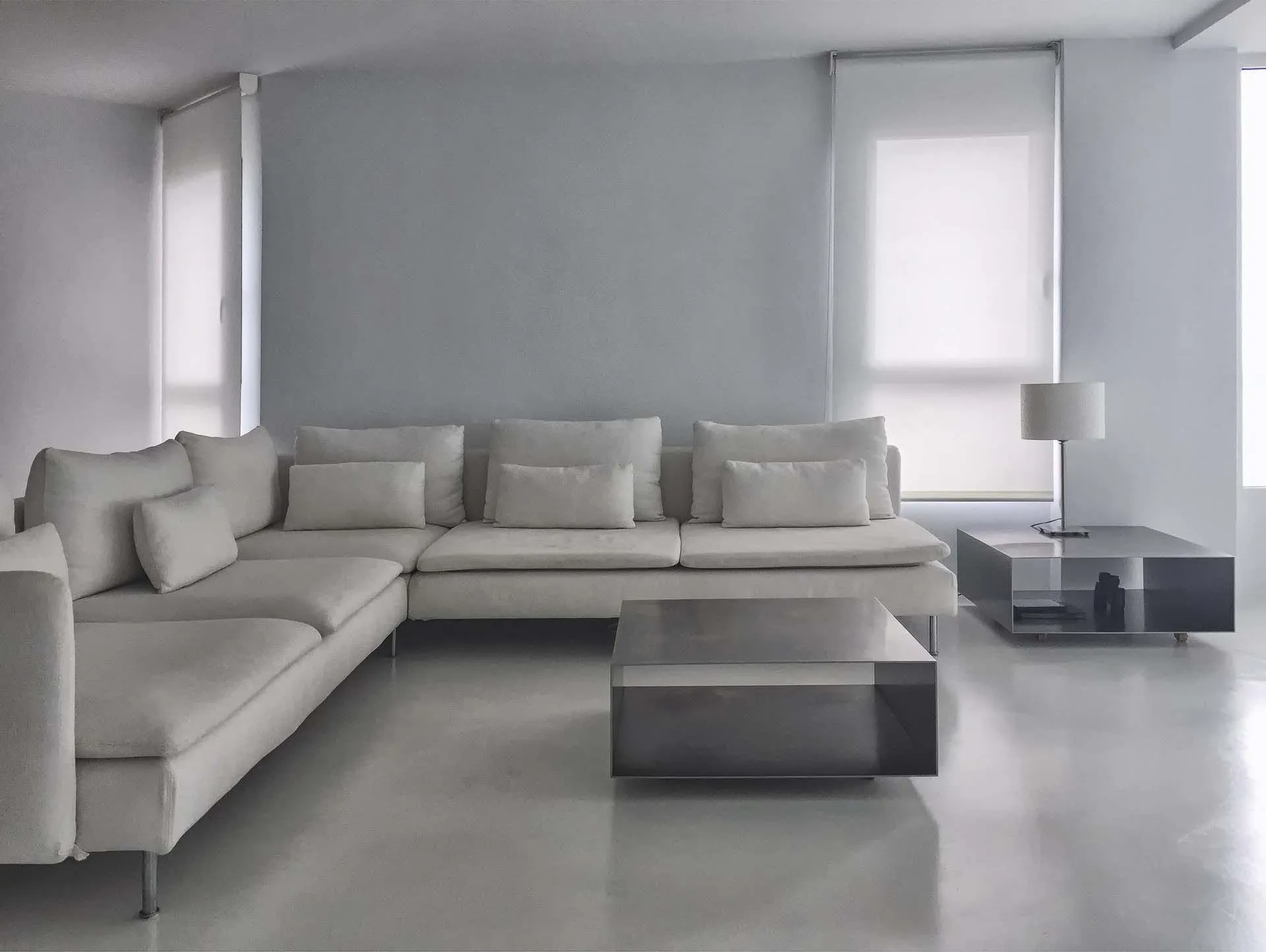 Living room with light grey polished microcement floor and a white corner sofa