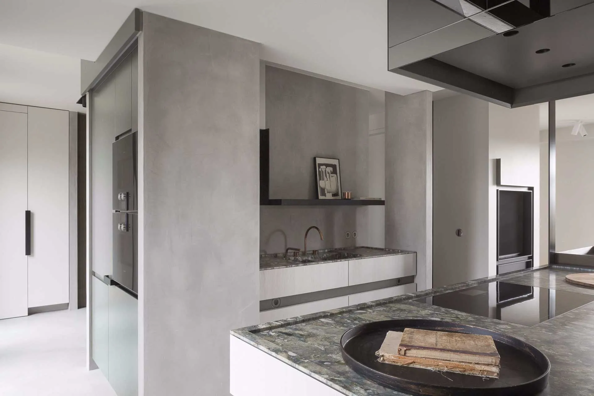 Kitchen with grey microcement walls, marble island worktop and integrated ovens