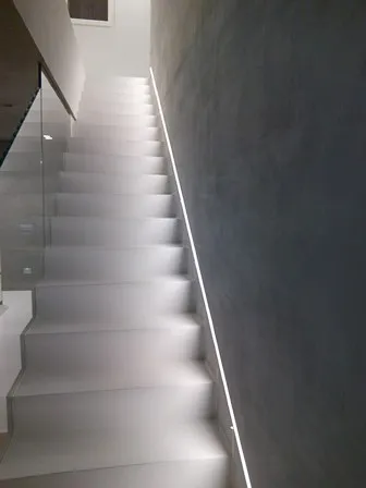 White microcement staircase with LED strip lighting beside a grey wall