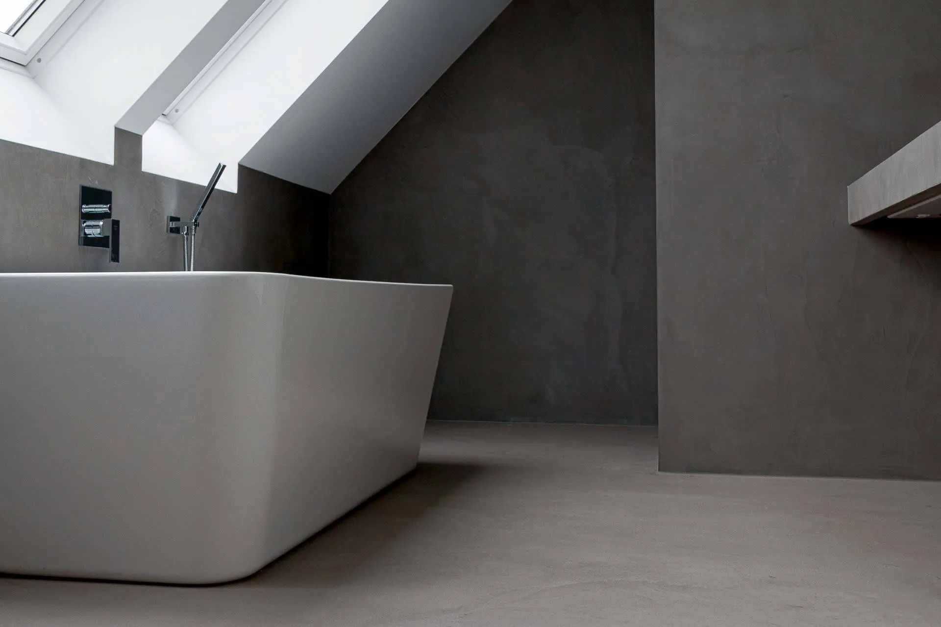 Loft bathroom with dark grey microcement walls and floor and a freestanding bath