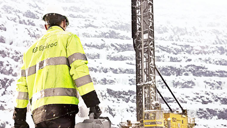 Man in yellow safety jacket walking towards an Epiroc drill.