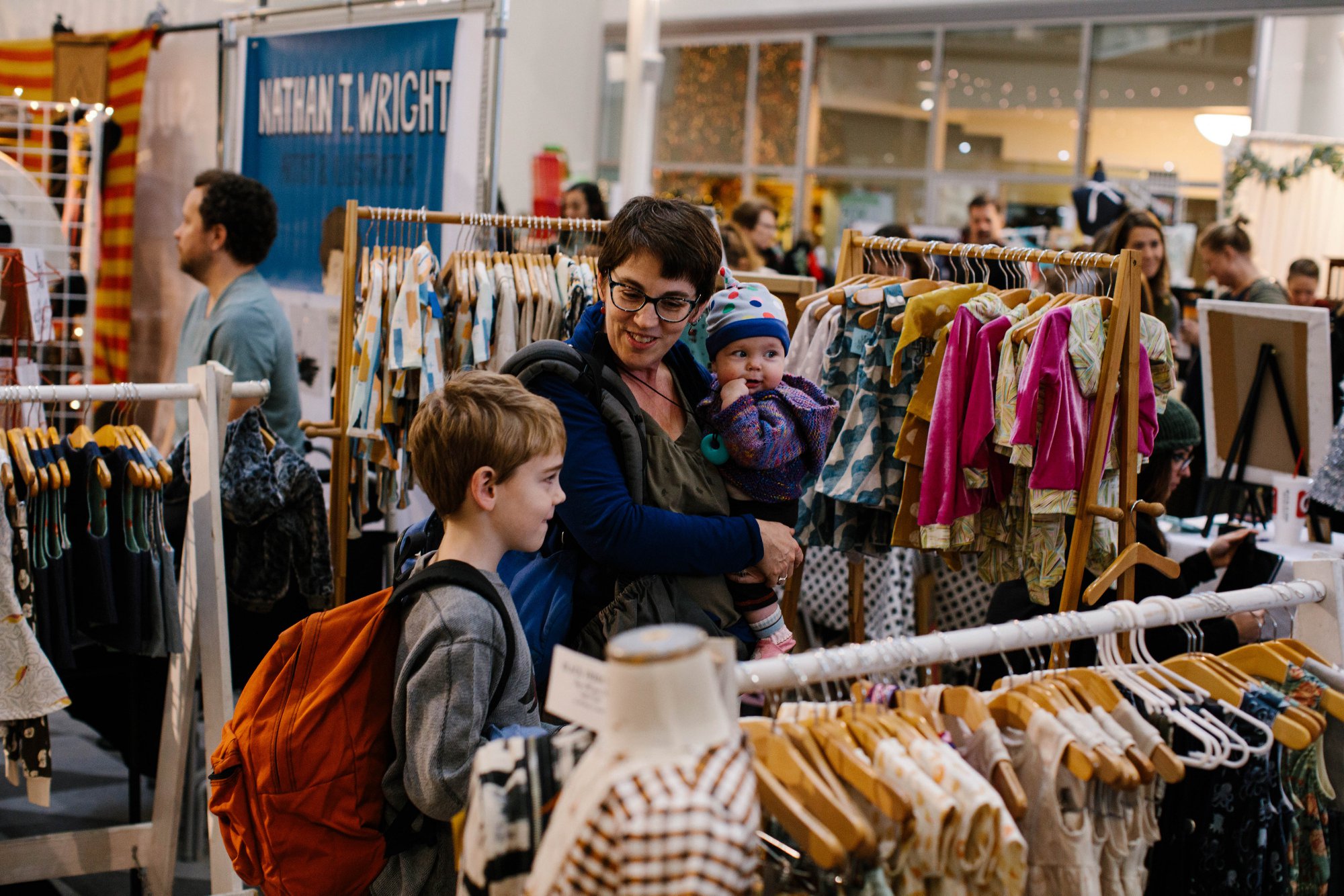   A family standing in front of a children’s clothing rack. 