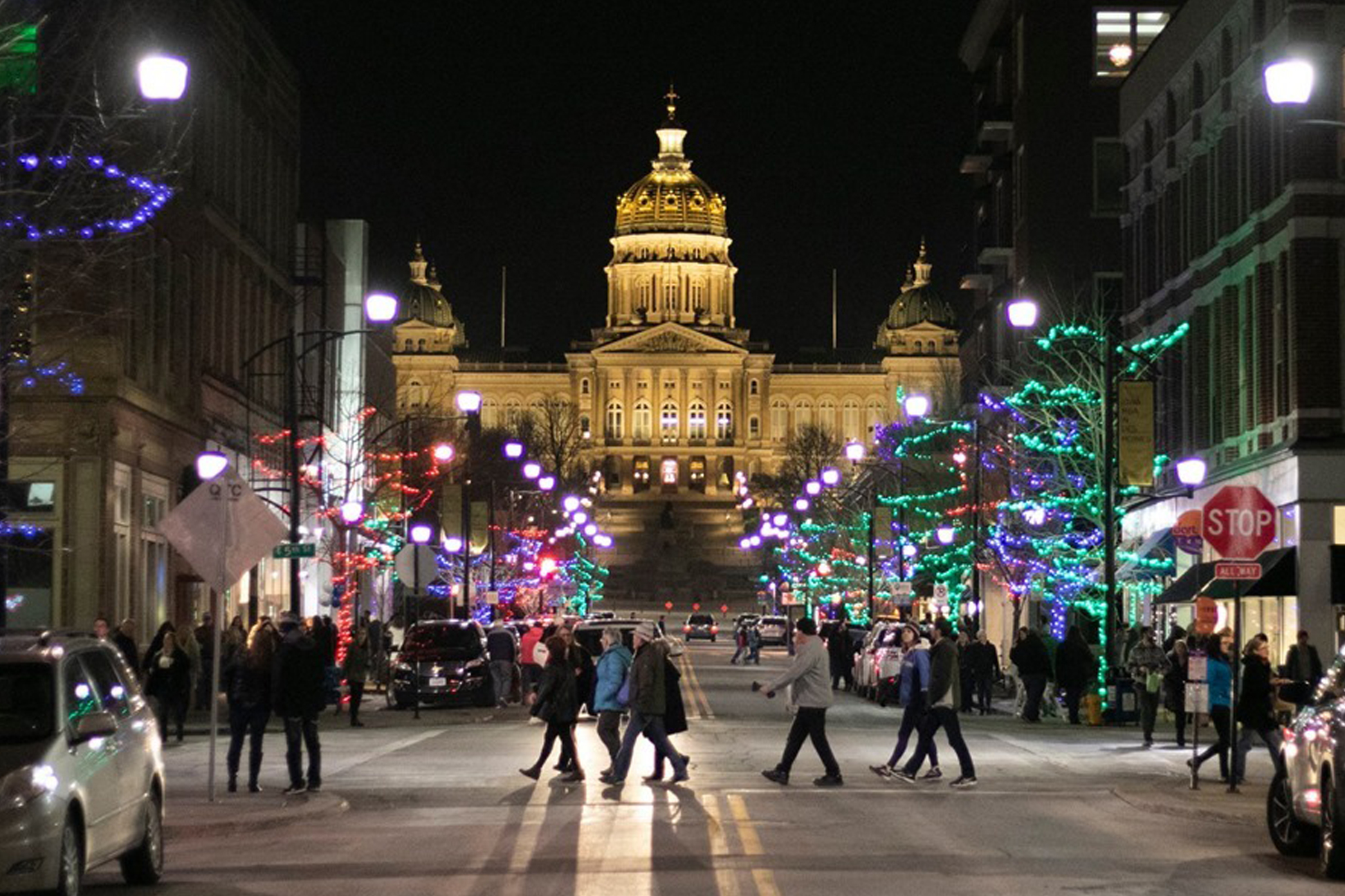 Bustling street with pedestrians, holiday lights and a view of the Iowa Capitol building.