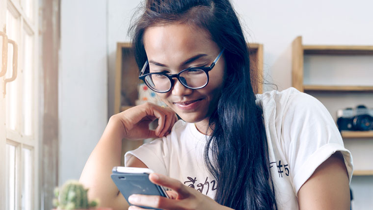 Young woman with glasses looking at her phone.