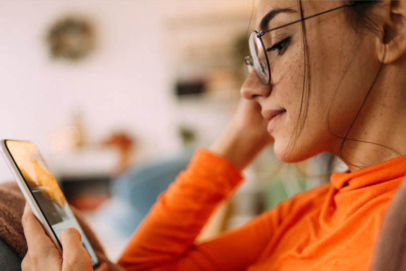 Woman in glasses looking at her cell phone.