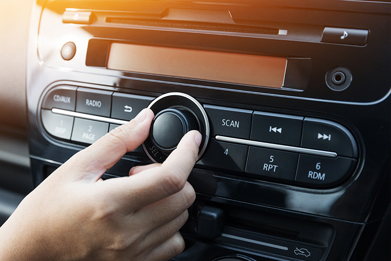 Person adjusting volume of their car stereo.