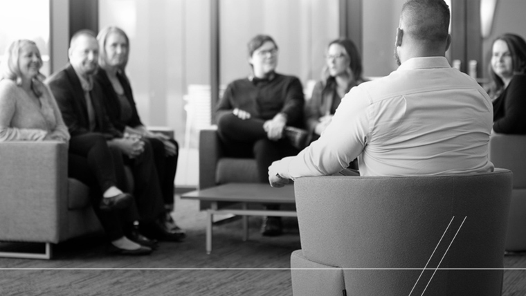 Group of people sitting on couches, conversing. 