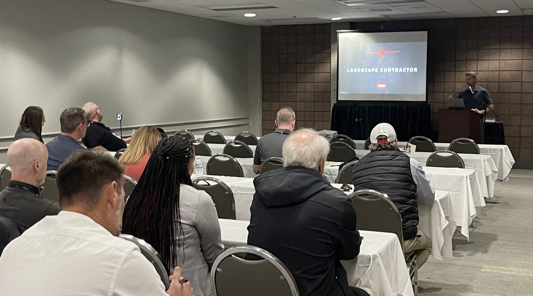 Presenter speaking to an audience in a conference room. 