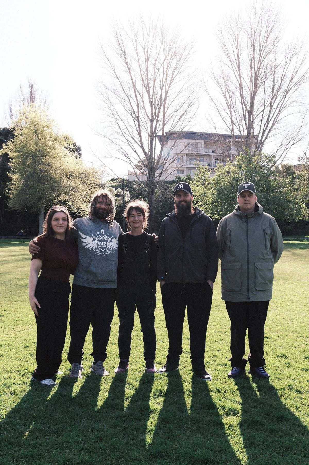 Chloe Moore, Aaron, Rose Kent-Wilson, Adam Lilburn and Carl Fenton stand together on a sunlit park lawn