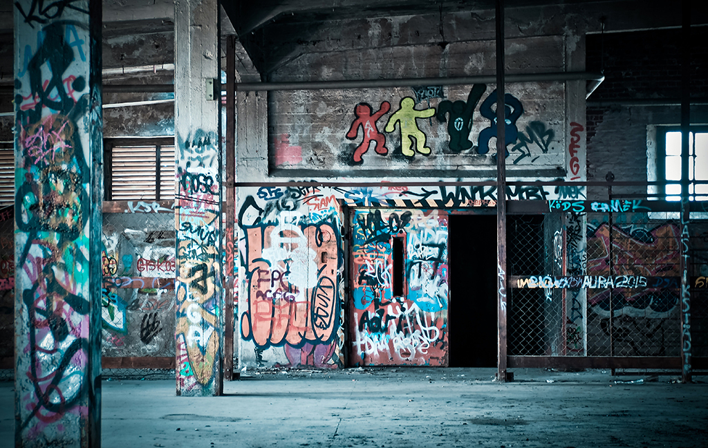 Ett övergivet industrilokal med väggar och pelare täckta av färgstark graffiti.
