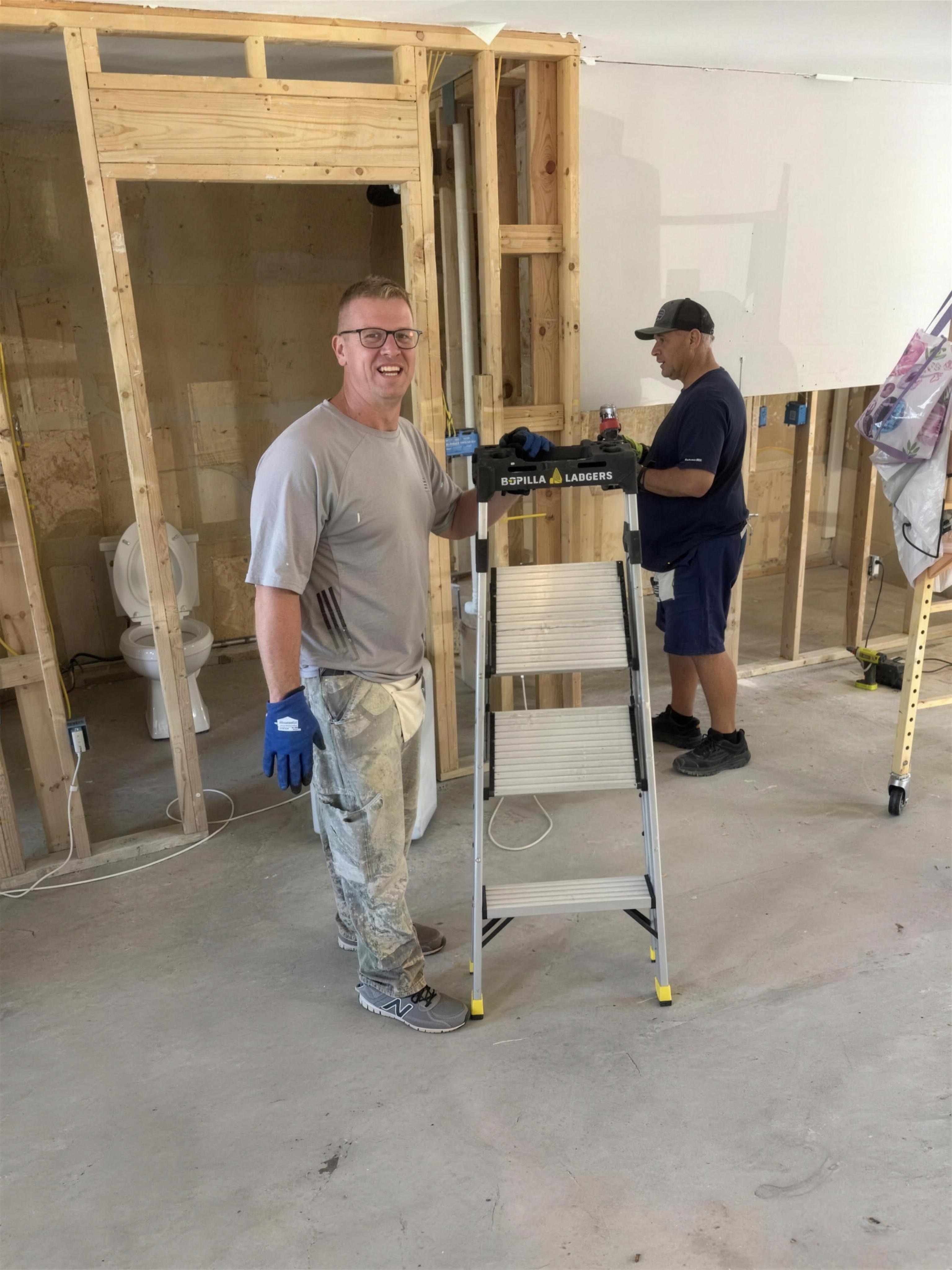 Two volunteers measuring interior framing during the rebuild
