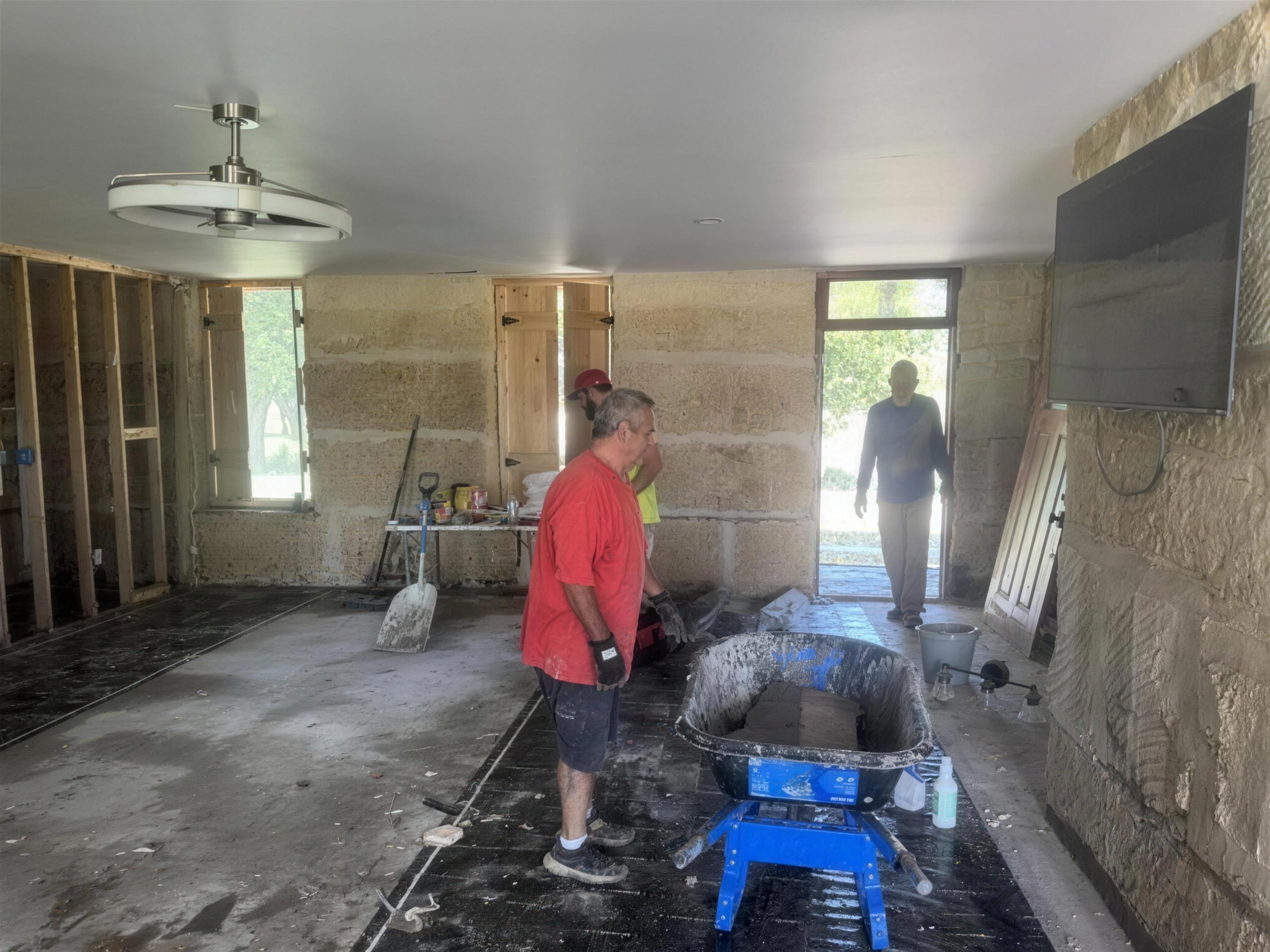 Volunteer moving a wheelbarrow of debris outside a flooded home